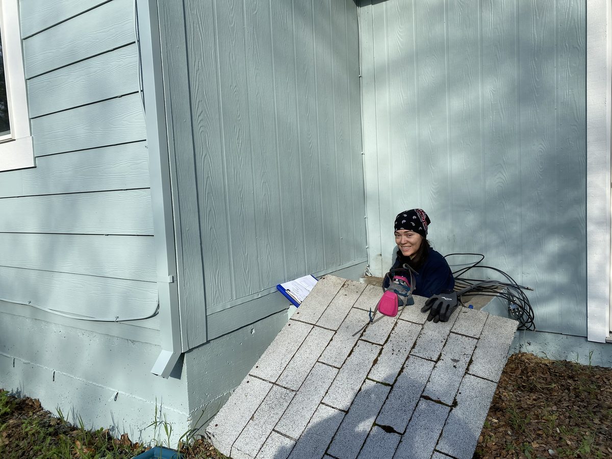 Christy Runnion, EIT, climbing out of the crawl space after inspecting the foundation of a manufactured home in the Sierra foothills